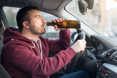 a man driving while drinking alcohol drink